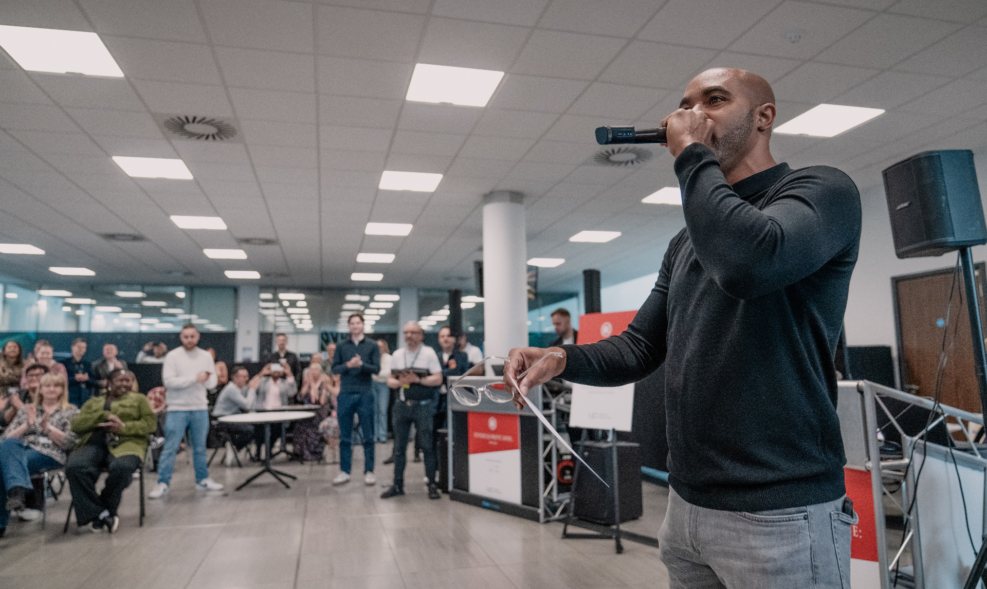 Shaun Benn hosting a corporate event with a microphone in front of a seated audience