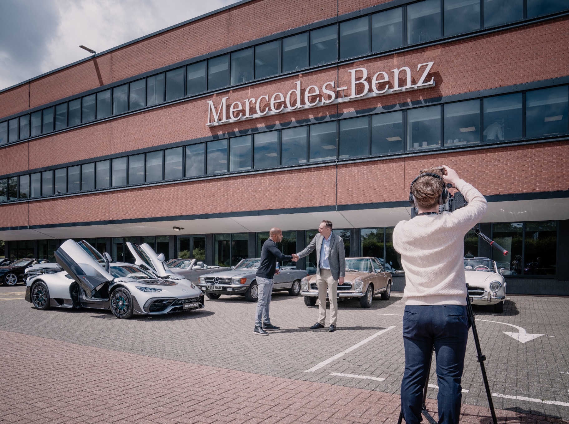 Shaun Benn filming a presentation outside Mercedes-Benz UK headquarters with classic and AMG cars